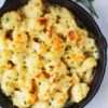 Garlic cauliflower gratin with a crispy golden topping in a white baking dish." Garlic cauliflower gratin with a crispy golden topping in a white baking dish.