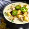 Creamy jalapeño soup served in a white bowl, topped with cilantro and croutons.