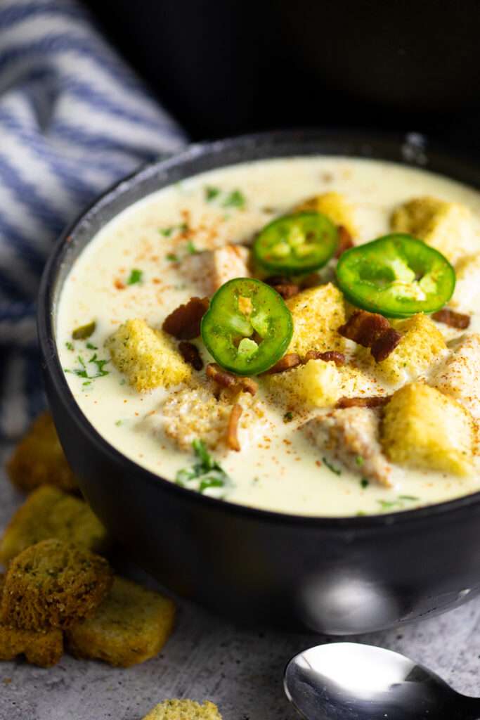 Creamy jalapeño soup served in a white bowl, topped with cilantro and croutons.