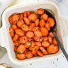 Honey-sriracha glazed carrots on a white plate with fresh herbs