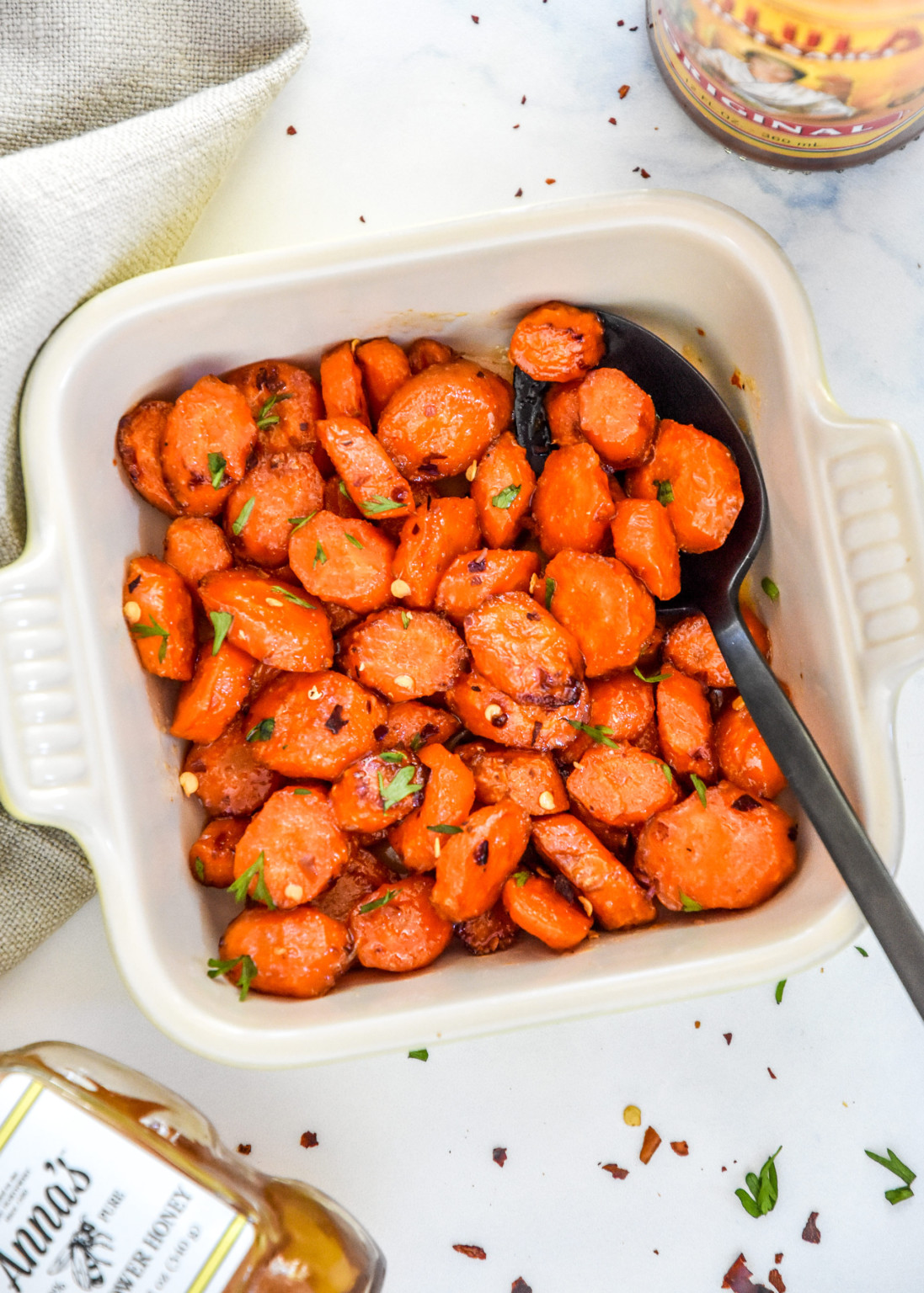 Honey-sriracha glazed carrots on a white plate with fresh herbs