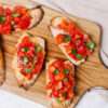 Toasted baguette slices topped with fresh tomatoes, basil, and olive oil.