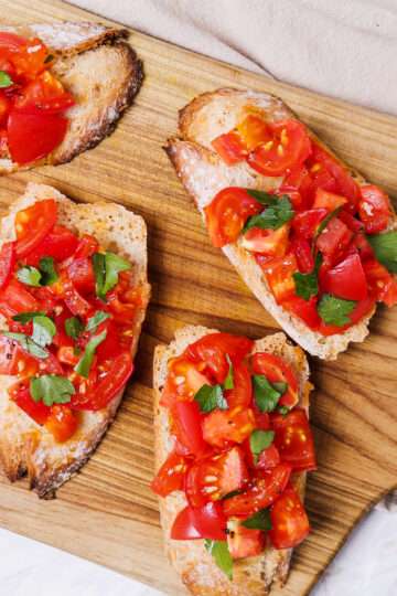 Toasted baguette slices topped with fresh tomatoes, basil, and olive oil.