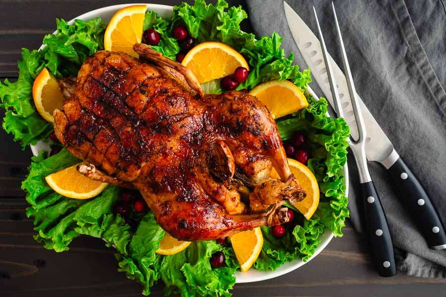 Maple-Glazed Roast Duck with Orange-Cranberry Sauce on a festive platter