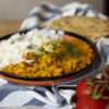 A vibrant plate of spicy chicken curry topped with fresh cilantro, served with basmati rice and naan bread.