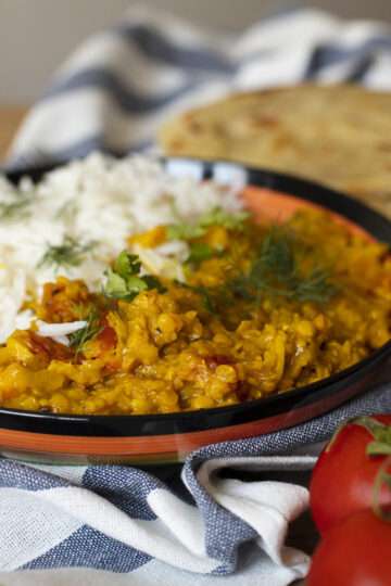 A vibrant plate of spicy chicken curry topped with fresh cilantro, served with basmati rice and naan bread.