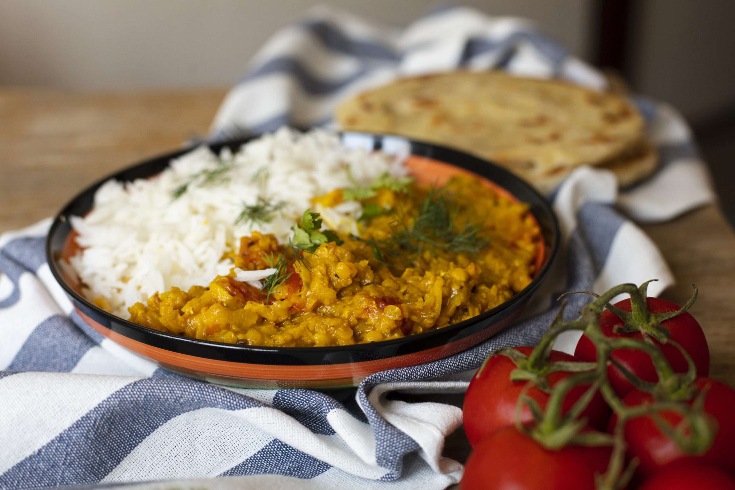 A vibrant plate of spicy chicken curry topped with fresh cilantro, served with basmati rice and naan bread.