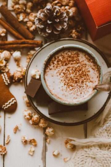 A mug of Gingerbread Hot Chocolate Surprise topped with whipped cream and a cinnamon stick