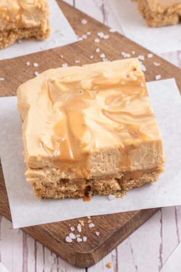 Squares of salted dulce de leche cheesecake bars with a drizzled caramel top