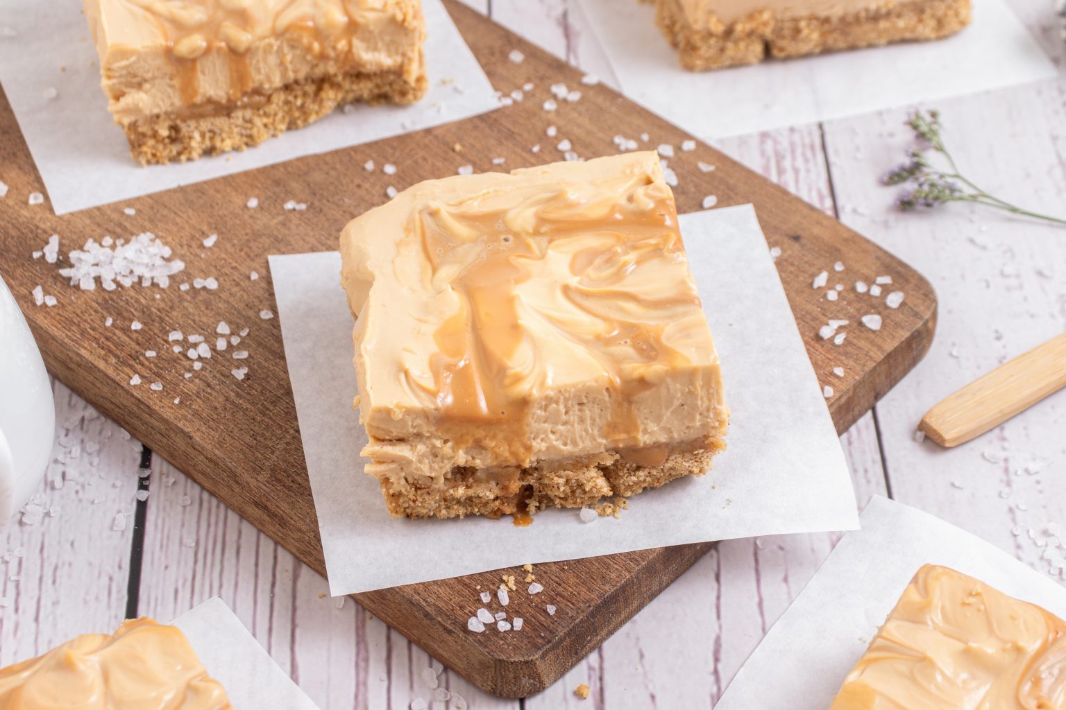 Squares of salted dulce de leche cheesecake bars with a drizzled caramel top