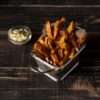 Crispy baked sweet potato fries with a spicy seasoning, served with a dipping sauce.