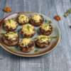 A platter of golden-brown, cheese-stuffed mushrooms garnished with fresh herbs.