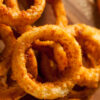 Crispy baked onion rings stacked high, with dipping sauce on the side