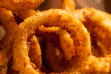 Crispy baked onion rings stacked high, with dipping sauce on the side