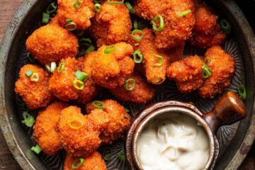 Fiery Buffalo Cauliflower Bites on a white plate garnished with celery and ranch dip.