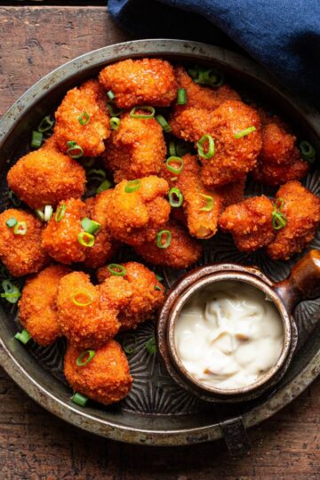 Fiery Buffalo Cauliflower Bites on a white plate garnished with celery and ranch dip.