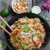 Chicken Pad Thai noodles with a lime wedge, peanuts, and fresh cilantro.