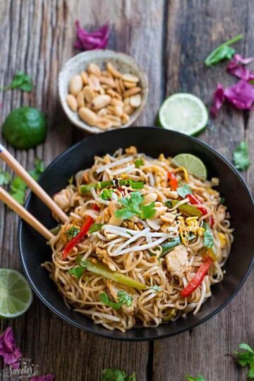 Chicken Pad Thai noodles with a lime wedge, peanuts, and fresh cilantro.