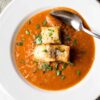 A bowl of roasted tomato basil soup topped with crispy, cheese-laden croutons.