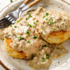 A plate of tall buttermilk biscuits and sausage gravy.