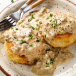 A plate of tall buttermilk biscuits and sausage gravy.