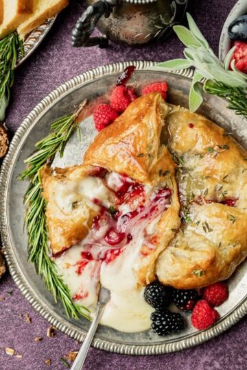 Brie en Croûte with Raspberry Jam in puff pastry, sliced open, showing melted cheese.