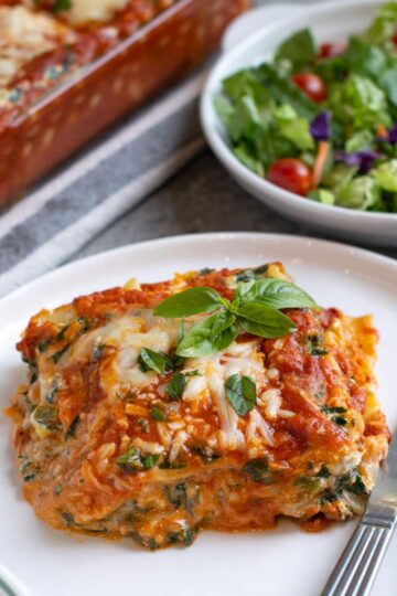 A slice of spinach ricotta lasagna with bubbly cheese on top