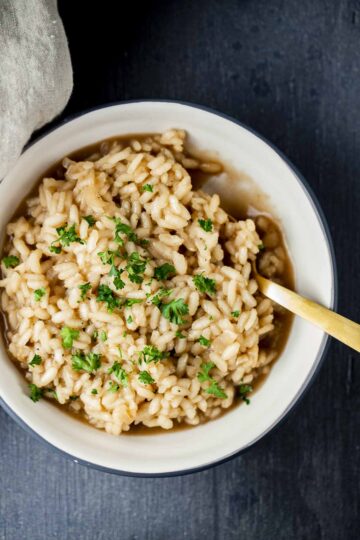 Creamy Truffle Risotto in a white bowl, garnished with Parmesan shavings and fresh herbs.