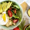 Quinoa Breakfast Bowl topped with poached eggs, fresh spinach, and a squeeze of lemon