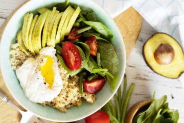 Quinoa Breakfast Bowl topped with poached eggs, fresh spinach, and a squeeze of lemon