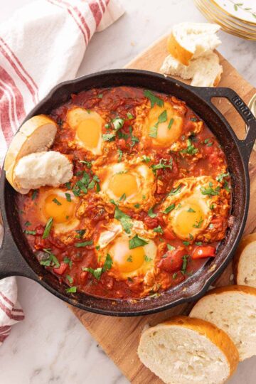 Shakshuka Recipe with vibrant tomatoes, bell peppers, and poached eggs in a rustic skillet