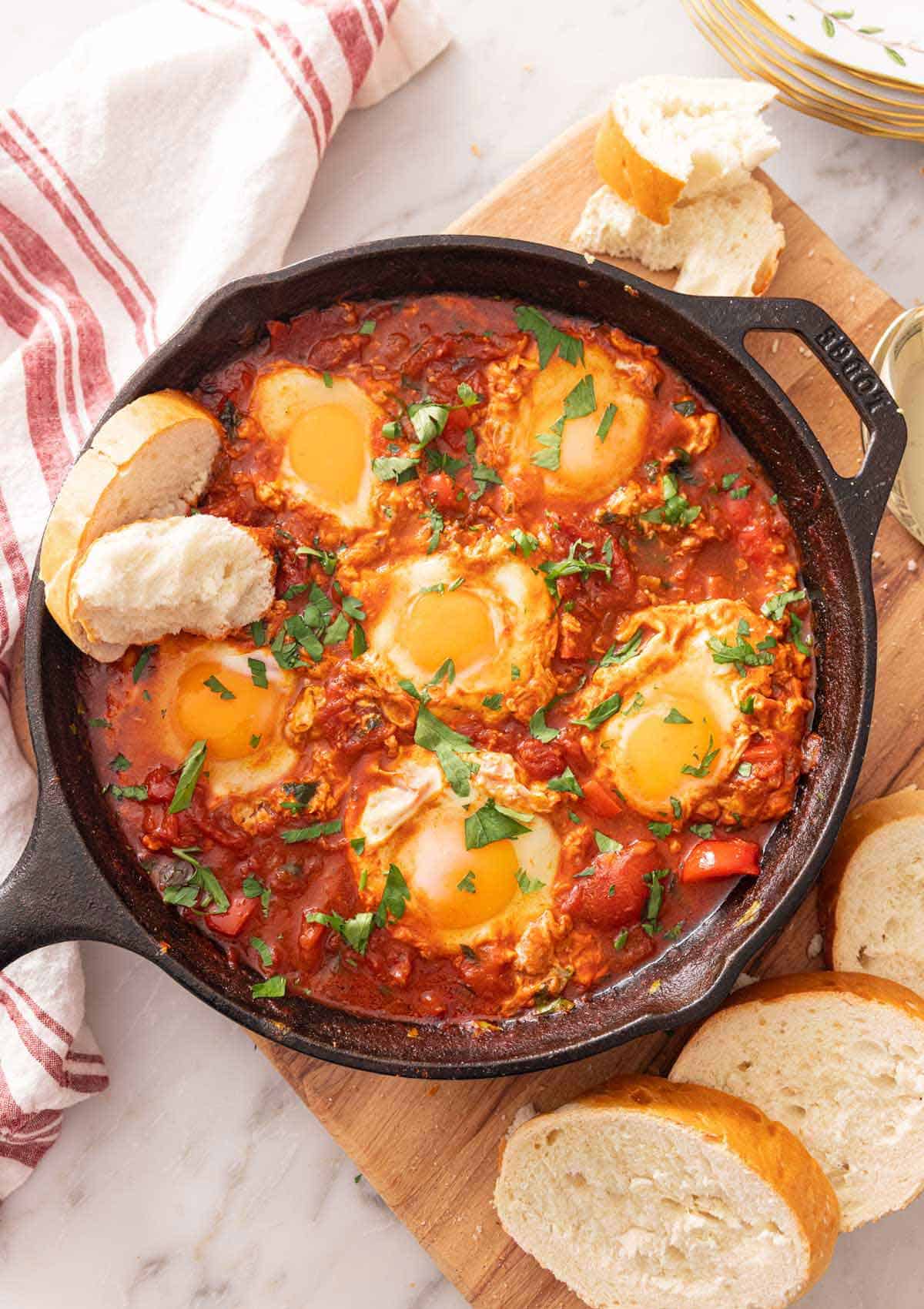 Shakshuka Recipe with vibrant tomatoes, bell peppers, and poached eggs in a rustic skillet