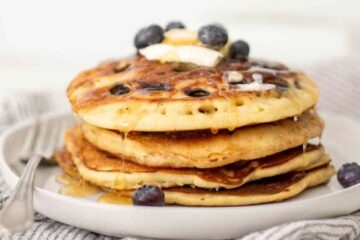 Nutrient-Packed Sourdough Pancakes topped with blueberries, banana slices, and a drizzle of maple syrup