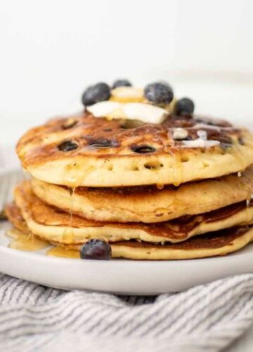 Nutrient-Packed Sourdough Pancakes topped with blueberries, banana slices, and a drizzle of maple syrup