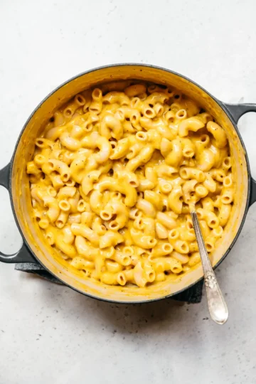 Vegan Mac and Cheese in a rustic bowl, drizzled with a sprinkle of vegan parmesan and garnished with herbs