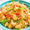 Thai Peanut Butter Chicken with Noodles topped with chopped peanuts, fresh cilantro, and lime wedges.