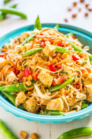 Thai Peanut Butter Chicken with Noodles topped with chopped peanuts, fresh cilantro, and lime wedges.