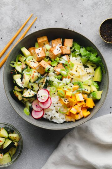 Vegan Poke Bowl with marinated tofu, sushi rice, edamame, avocado, cucumber, and a sesame-soy dressing